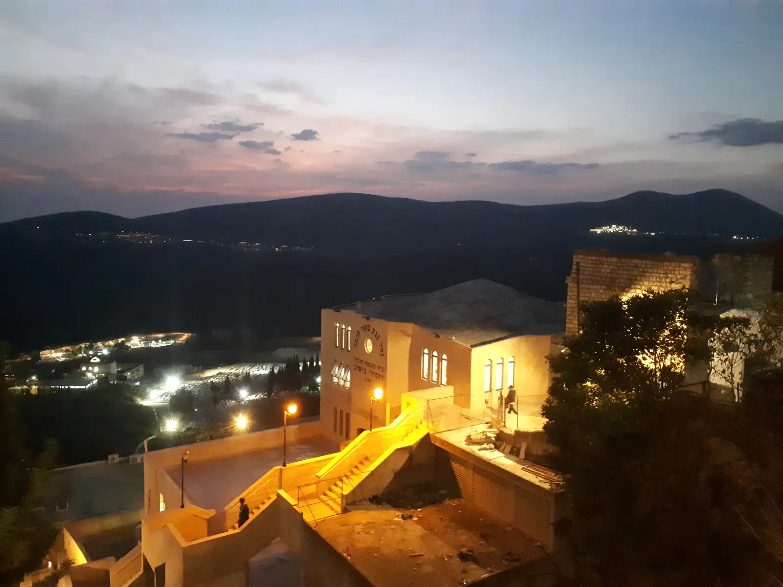 Lights coming on over the old city of Tzfat at dusk, with the Galilee hills beyond